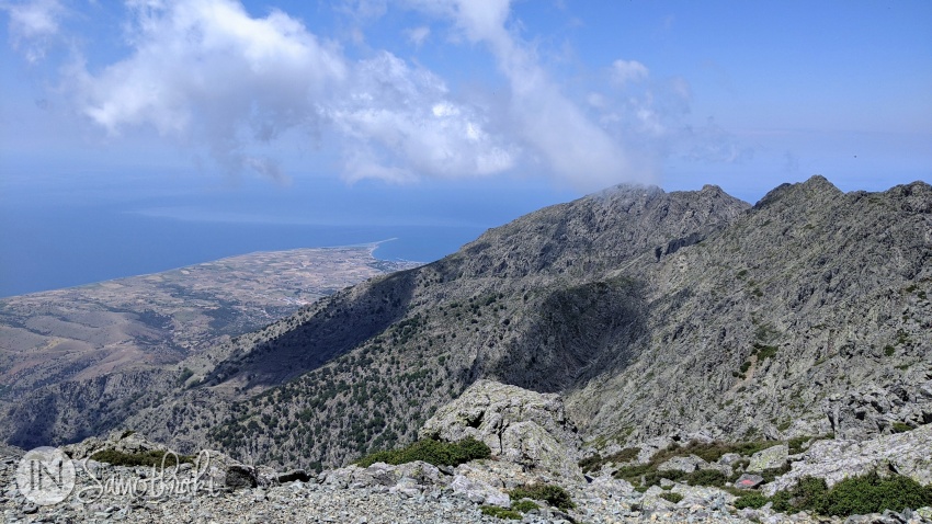 A red arrow on a rock points the way toward Chora. In the distance, you can see Kamariotissa Bay.
