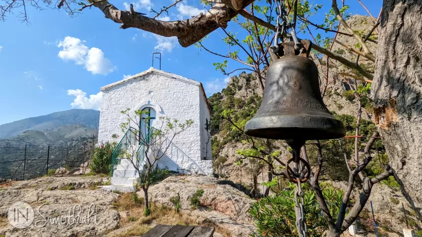 A bell hangs from a tree.