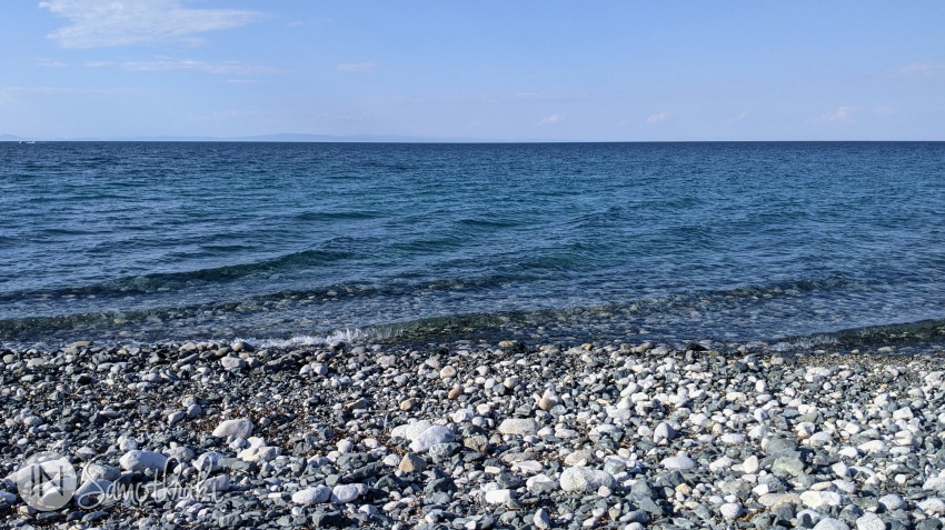 The water is clear, stones, gravel and a little sand cover the beach.